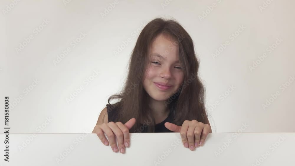 Beautiful girl teenager looks at a poster with information and expresses satisfaction on white background stock footage video. Beautiful girl teenager looks at a poster with information and expresses satisfaction on white background stock footage video.