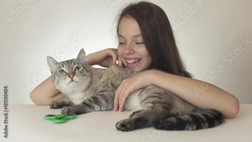 Beautiful cheerful teen girl with a cat playing with green fidget spinner on white background stock footage video photo