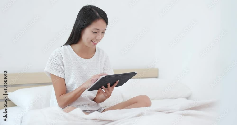 Woman use of tablet and sitting on bed Woman use of tablet and sitting on bed