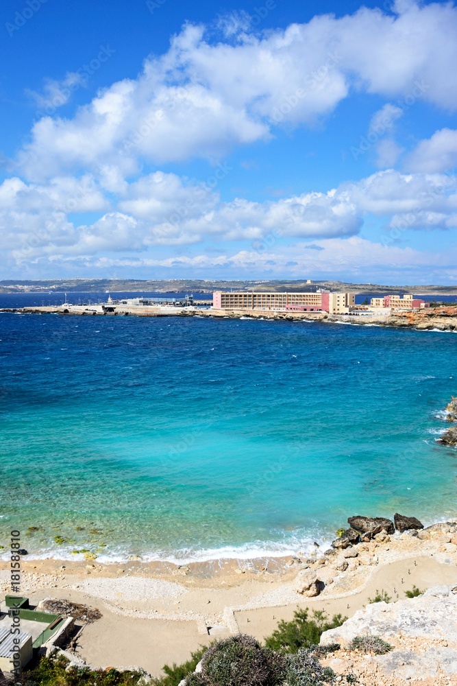 Rocky coastline with hotels and ferry terminal to the rear, Paradise Bay, Malta.