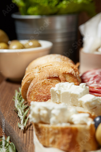 Cheese, vegetables, fruits and spices. Bread, olives and crackers. Mediterranean diet and cuisine. Dark background.