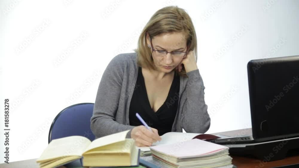 female teacher checks homework in classroom in front of laptop female teacher checks homework in classroom in front of laptop