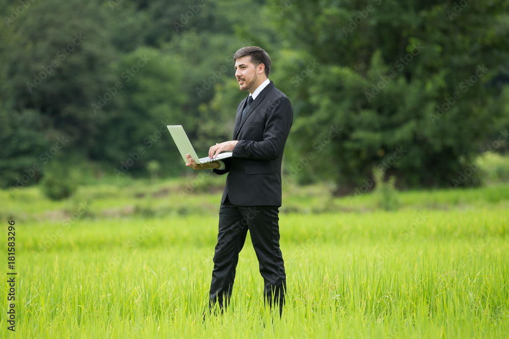 Agronomist Using a laptop for read a report and standing in an agriculture field.