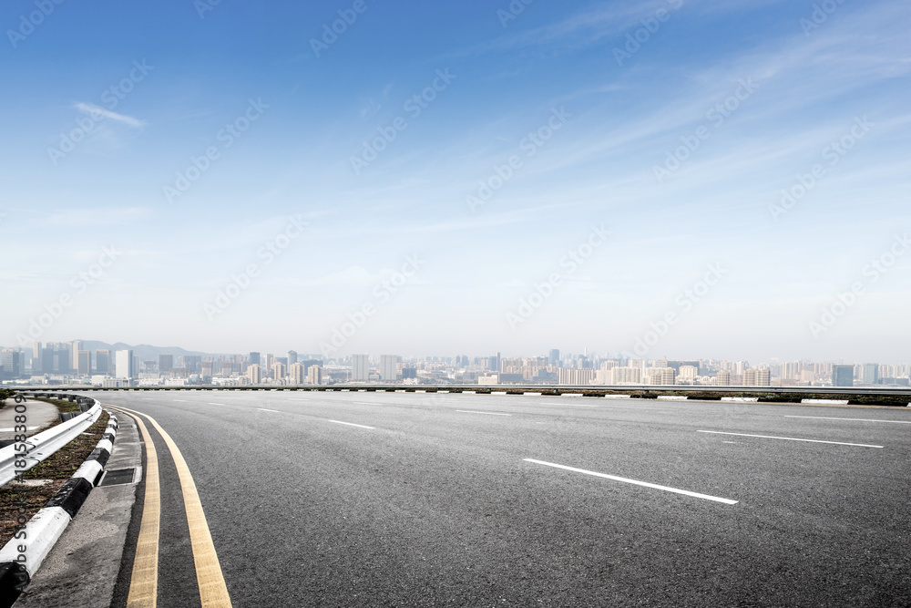 Fototapeta premium empty asphalt road with modern cityscape in foggy day