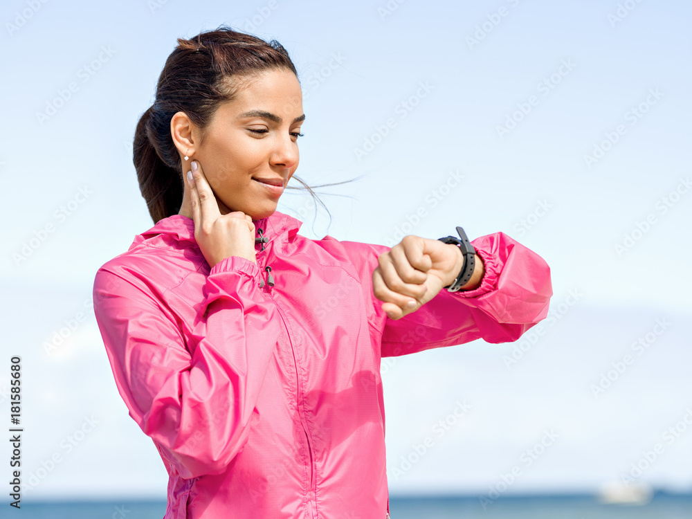 Young woman on beach checking heart rate after run Young woman on beach checking heart rate after run