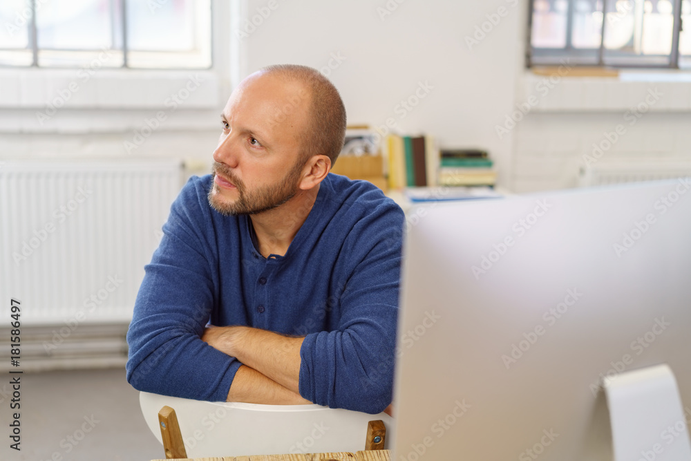 Fototapeta premium mann sitzt am computer und schaut mit ernstem blick zur seite