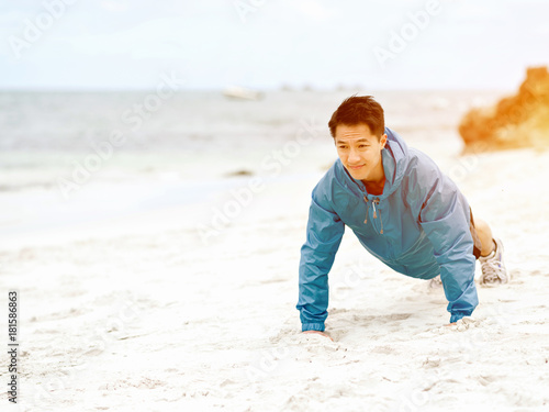 Young man doing exercise at the beach © Sergey Nivens