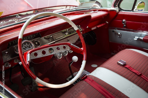 Isolated Interior View of Restored Vintage Automobile with Red Dashboard, Red and White Steering Wheel and Fabric Seats © Jacquie Klose