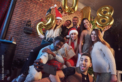 Group of cheerful friends makes selfie. New 2018 Year is coming. Celebrate the new year in a cozy home atmosphere