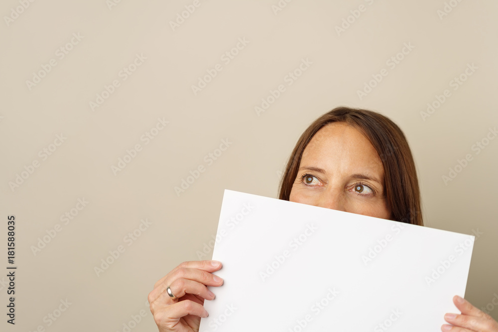 frau hält ein schild vor ihr gesicht und schaut zur seite frau hält ein schild vor ihr gesicht und schaut zur seite