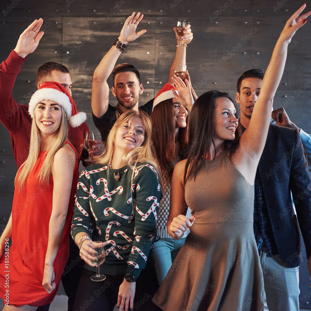 Fototapeta premium Party with friends. They love Christmas. Group of cheerful young people carrying sparklers and champagne flutes dancing in new year party and looking happy. Concepts about togetherness lifestyle