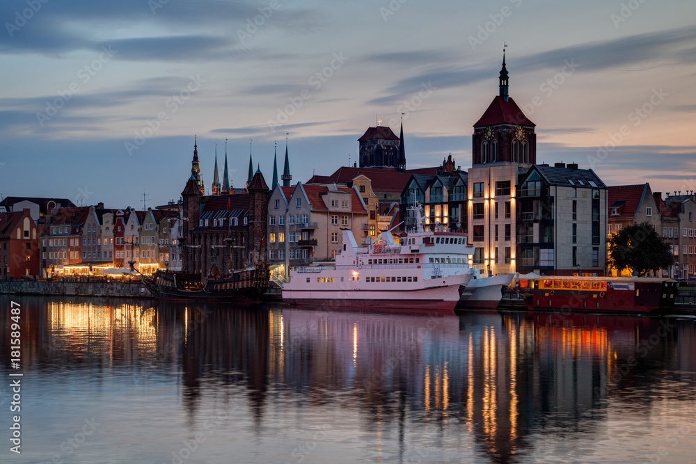 Obraz premium View of two boats and old buildings at the Long Bridge waterfront at the Main Town (Old Town) in Gdansk, Poland, in the evening.