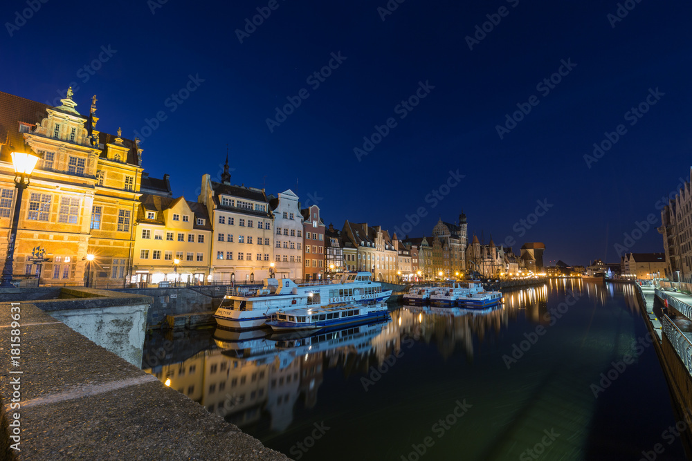 View of the lit Green Gate and other old buildings on the Long Bridge waterfront at the Main Town (Old Town) and Motlawa River in Gdansk, Poland, in the evening. 