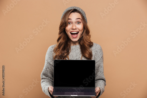 Canvastavla Portrait of happy exited brunette woman holding and showing blank laptop screen