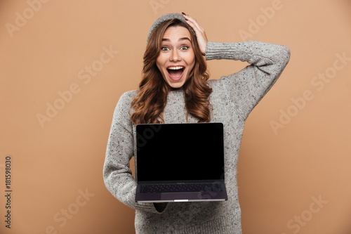 фотографія Close-up photo of young overjoyed brunette woman in warm clothes holding her hea
