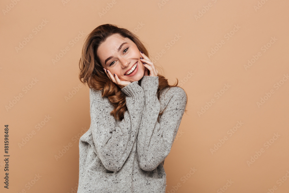 Portrait of cute smiling brunette girl in soft sweater touching her face while looking at camera Portrait of cute smiling brunette girl in soft sweater touching her face while looking at camera