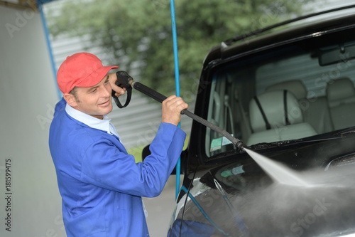 mature man washing a car with pressured water