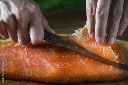 Cocinero cortando lonchas de salmón en salazón para marinar y preparar sushi y otras comidas