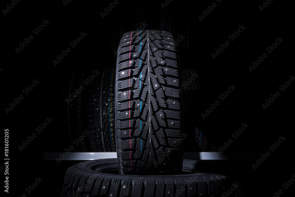 Winter tire on the background of racks with tires Winter tire on the background of racks with tires