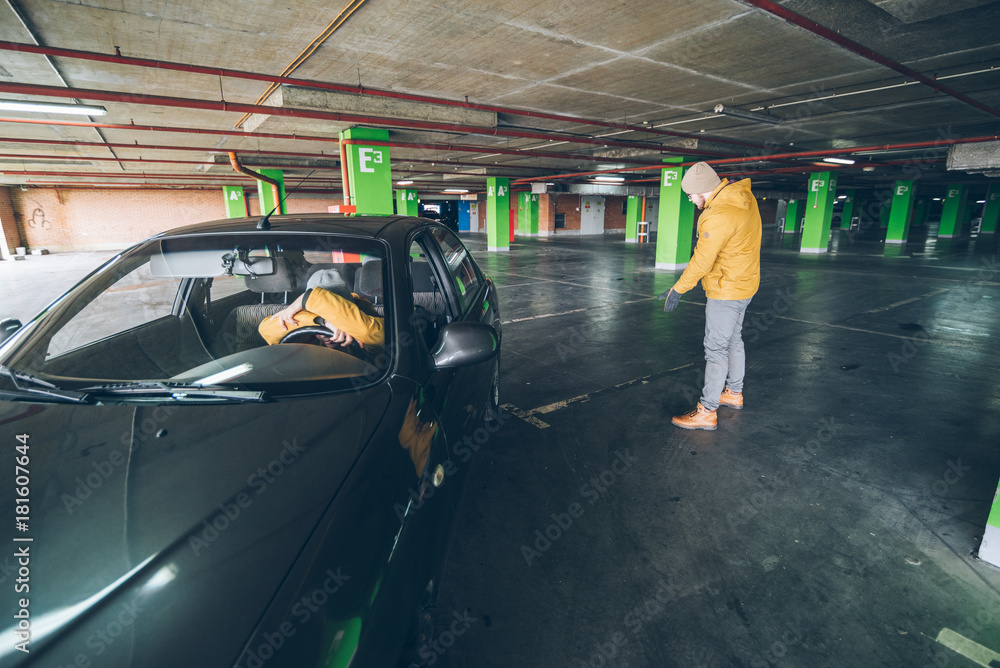 Fototapeta premium young woman parking car in underground parking with man help