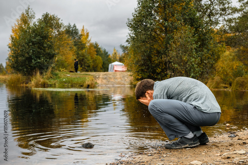 Man washing on the lake bank in overcast day, Leningrad Region, Russia