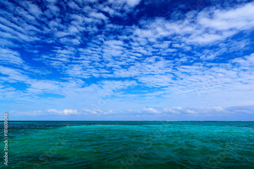 Sea in Caribbean with blue sky and white cloud. Water surface in ocean. Beautiful morning twilight sea landscape. Pink clouds with blue ocean waves. Water on sand beach. Green water near Mexico coast