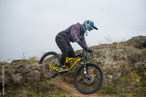 Professional Cyclist Riding Mountain Bike Down the Rocky Hill. Extreme Sport and Enduro Biking Concept.