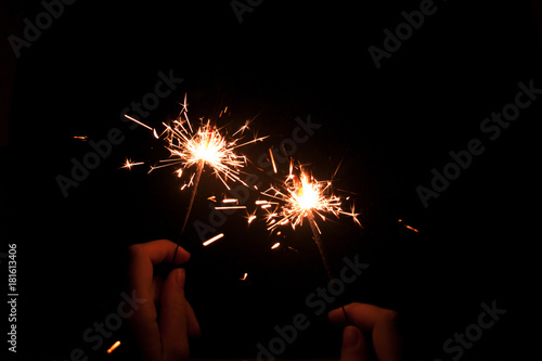 Sparkler background / A sparkler is a type of hand-held firework that burns slowly while emitting colored flames, sparks, and other effect