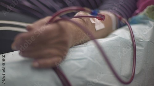 Wrinkled hand of mature hemodialysis patient during peritoneal dialysis treatment, machine pumps blood focus change on tube injected in vein, macro shot, shallow depth of field, real scene, indoors photo