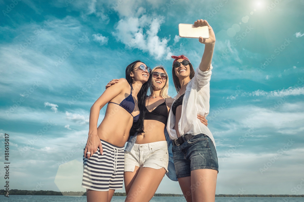 Three young pretty women in sunglasses having fun on the beach a