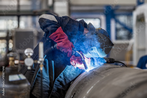 The welder in the mask welds the metal part photo