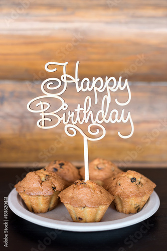 Birthday cakes and muffins with wooden greeting sign on rustic background. Wooden sing with letters Happy Birthday and holiday sweets. photo