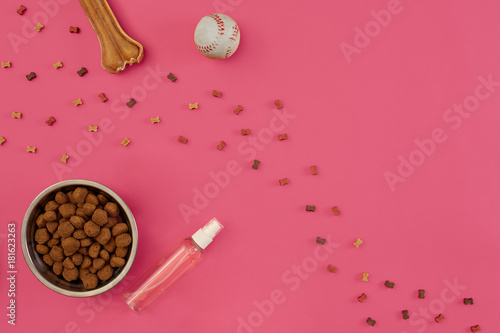 Dog snacks, dog chews, dog bone, ball toy for dog on a pink background with copy space