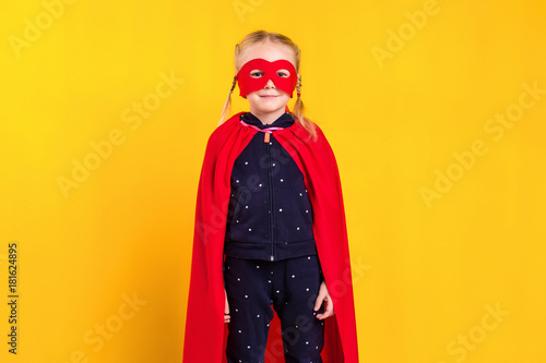 Superhero little girl in a red raincoat and a mask