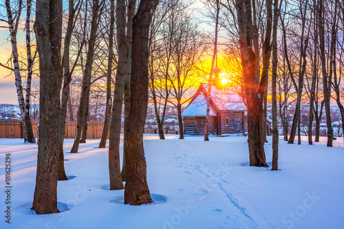 Small russian church in winter park at sunset