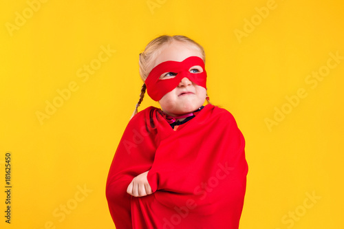 Funny little power superhero child girl in a red raincoat and a mask. Superhero concept.