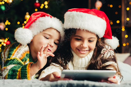 Christmas holidays at home. Happy children using tablet, playing online, having fun.