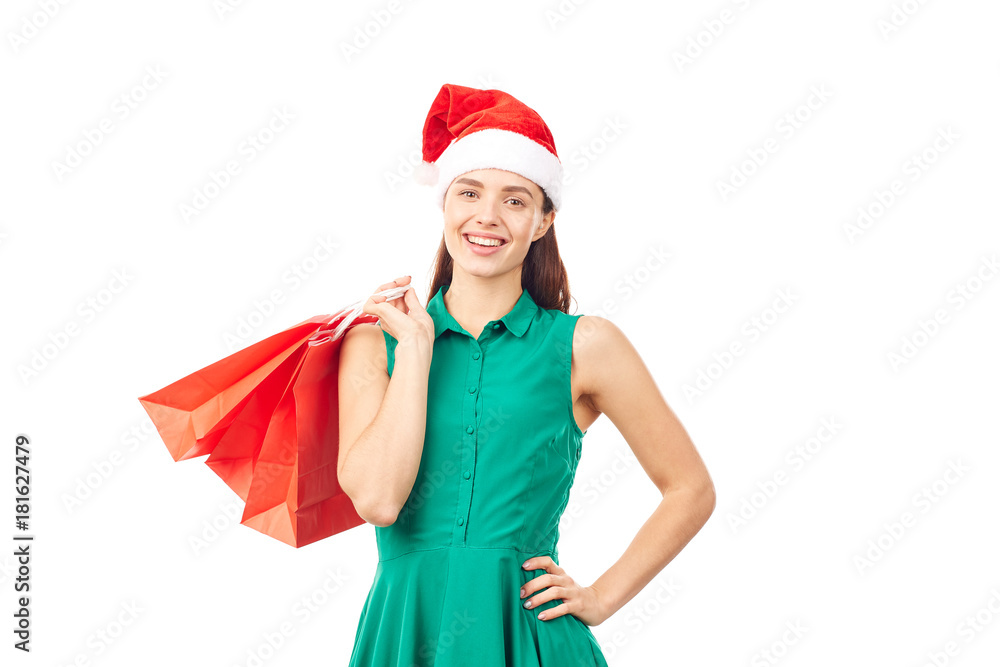Studio portrait of young woman in Santa hat posing with shopping bags on white background Studio portrait of young woman in Santa hat posing with shopping bags on white background