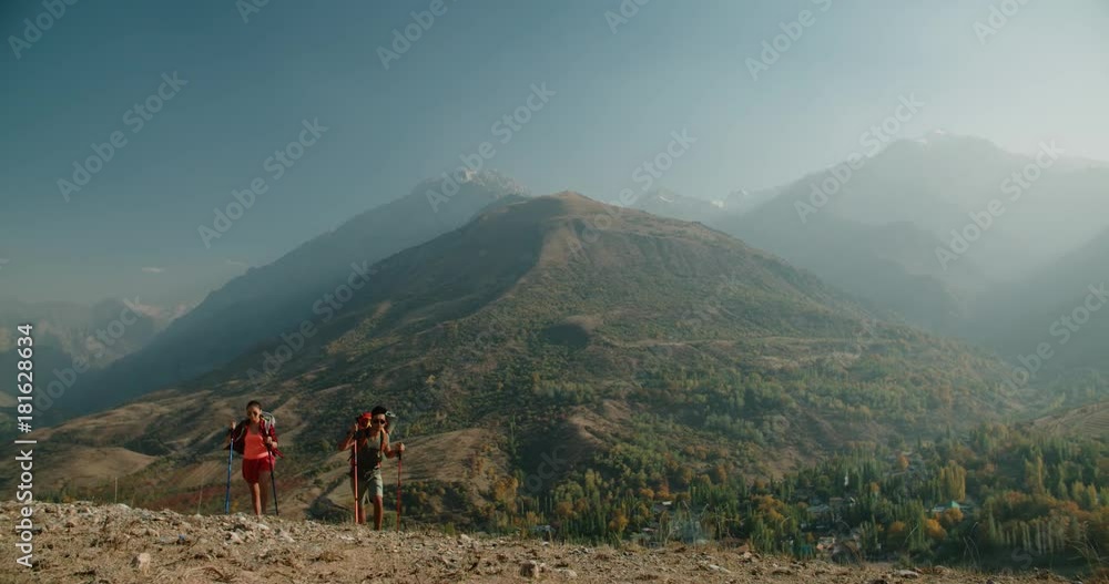 Hiking backpackers on hike in beautiful mountains landscape, trekking smiling happy together. Multiracial couple, young Asian woman and Indian man Hiking backpackers on hike in beautiful mountains landscape, trekking smiling happy together. Multiracial couple, young Asian woman and Indian man