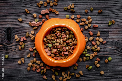 dry cat food in bowl on wooden background top view