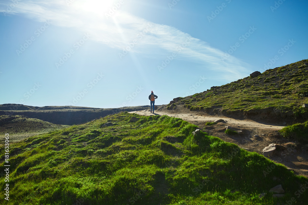 back view of woman traveler with small orange backpack on a walk in the Valley of the river of Hveragerdi Iceland. Hiking Tour of Reykjadalur Hot Springs back view of woman traveler with small orange backpack on a walk in the Valley of the river of Hveragerdi Iceland. Hiking Tour of Reykjadalur Hot Springs