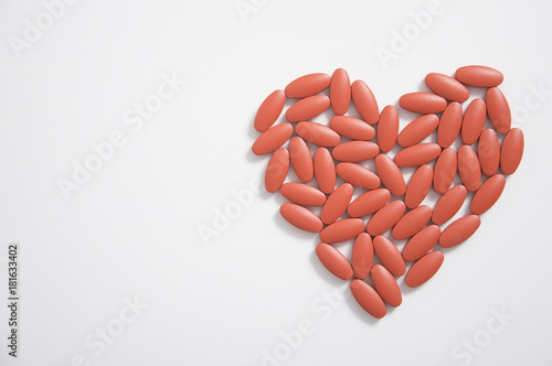 The heart made of tablets and pills on white background photo