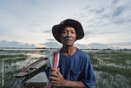 Fototapeta Photo portrait of the elderly native Fisher,who are out fishing in the river with boats background