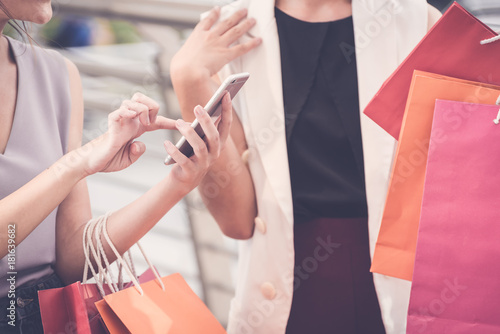 Women with the joy of shopping is using the phone during the shopping and holding shopping bags in hands,online shopping,social media concept.