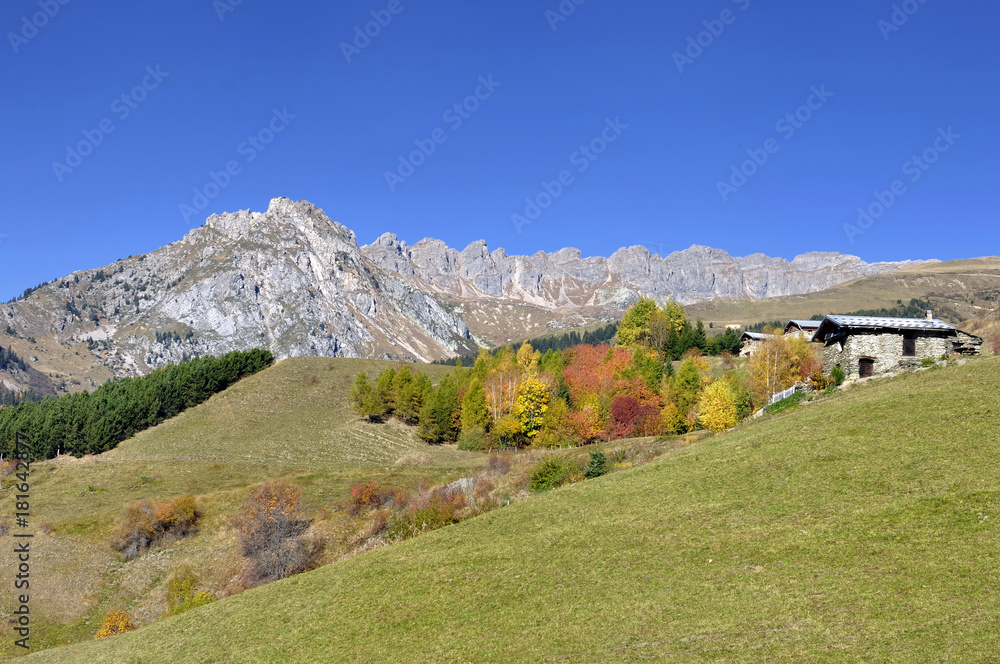 Naklejka premium peak mountain and cottage on a hill in autumn under blue sky 