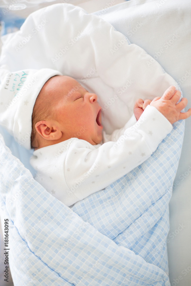 Newborn baby laying in crib in prenatal hospital Newborn baby laying in crib in prenatal hospital
