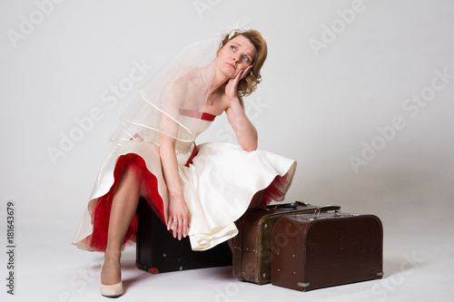 Sad bride with suitcases on white background in studio