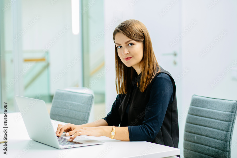 Image of a confident young woman sitting at working desk. Business, work and people concept. Image of a confident young woman sitting at working desk. Business, work and people concept.