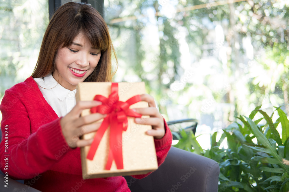 woman wearing red sweater holding gift box at home. girl with present box. christmas, new year holiday. birthday, anniversary celebration. woman wearing red sweater holding gift box at home. girl with present box. christmas, new year holiday. birthday, anniversary celebration.