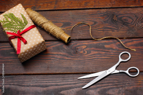 Tools for making Christmas gift box lie on a wooden table. a tangle of natural with silver scissors.